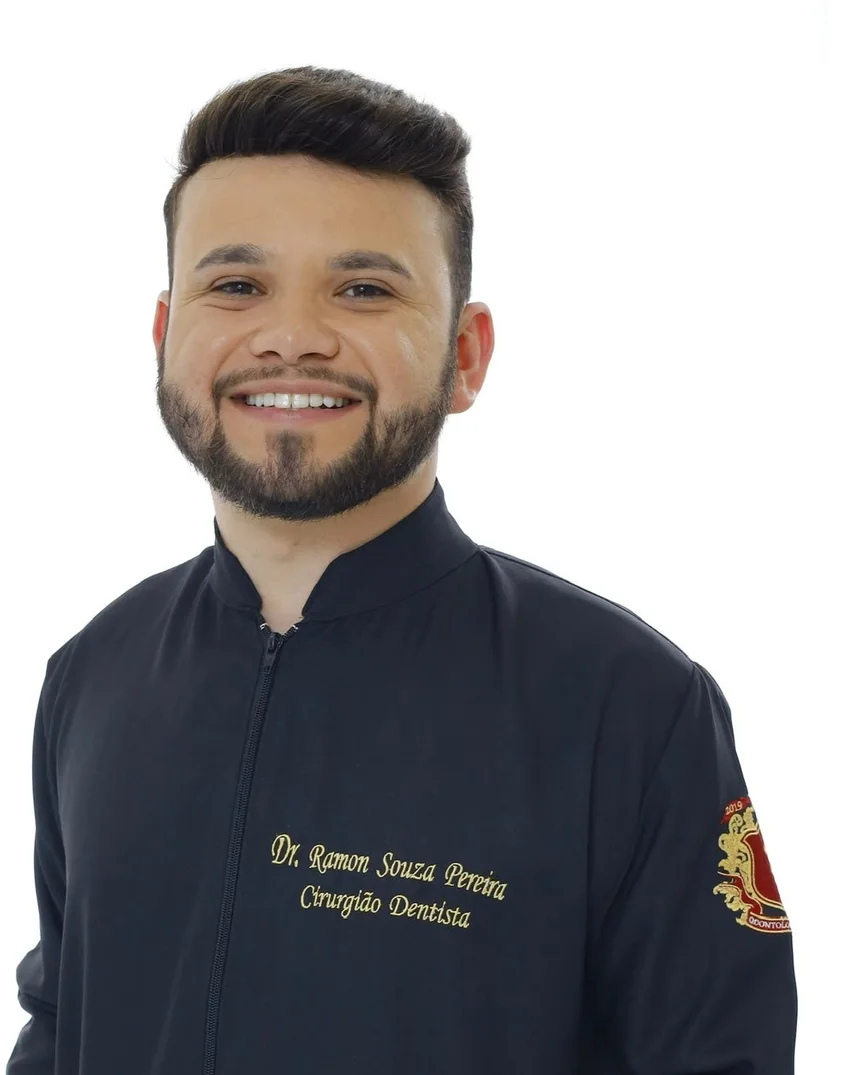 Dr. Ramon Souza de jaleco branco, de braços cruzados, no consultório em Piranguinho